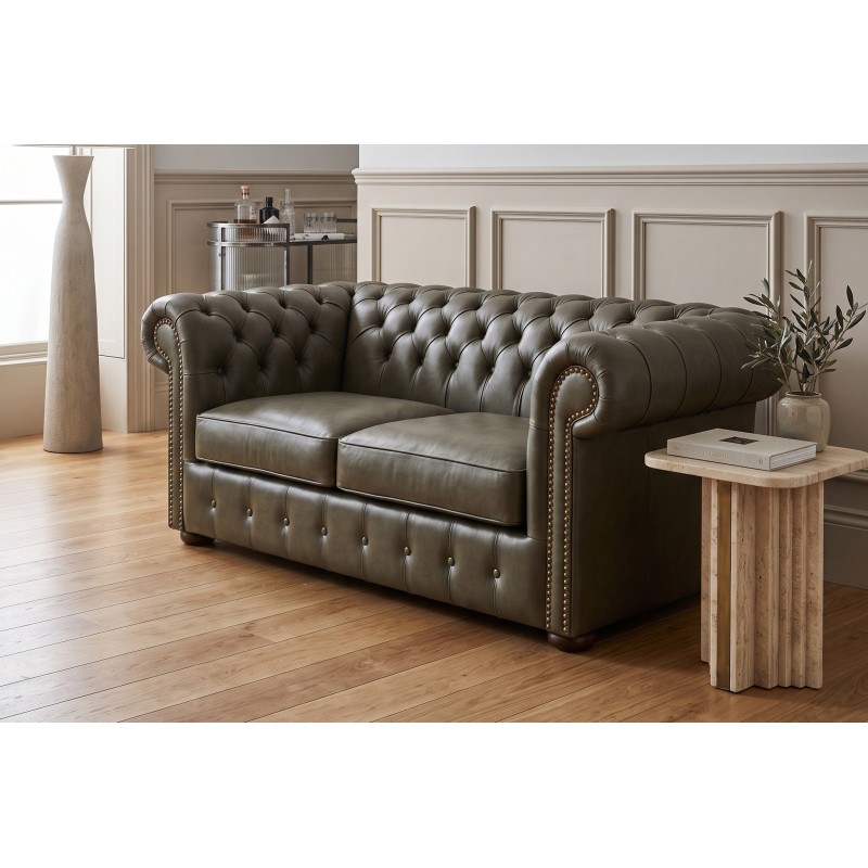 Kanapa chesterfield Noble w oliwkowoszarej skórze obok kamiennego stolika Kanapa chesterfield Noble w oliwkowoszarej skórze obok kamiennego stolika