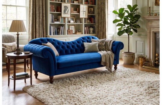 Sofa chesterfield z falistym oparciem Isla 230 cm w kobaltowym welurze w salonie z regałem na książki