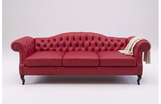 Czerwona trzyosobowa sofa chesterfield z białym kocem na gładkim tle