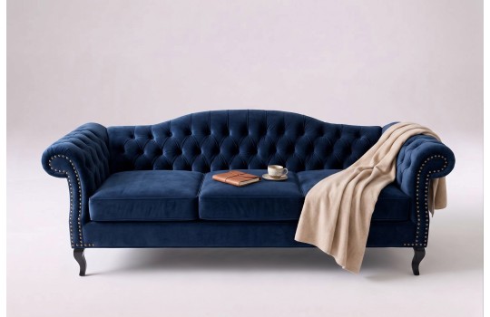 Ciemnoniebieska pikowana sofa Solano z jasnym pledem na toczonych nóżkach