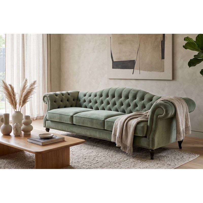 Szałwiowa sofa welurowa chesterfield Solano z jasnym pledem przy drewnianym stoliku