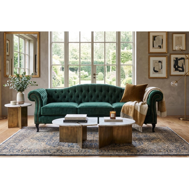 Butelkowozielona sofa chesterfield Solano w eleganckim salonie z dużym oknem i dywanem