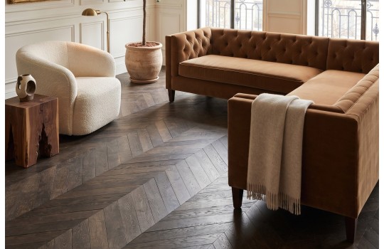Brązowy narożnik chesterfield Salsa w eleganckim salonie z ciemną drewnianą podłogą