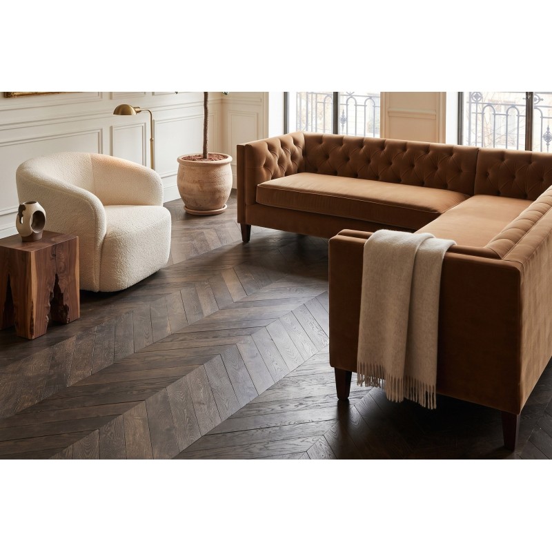 Brązowy narożnik chesterfield Salsa w eleganckim salonie z ciemną drewnianą podłogą