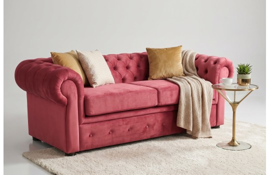 Sofa retro chesterfield w kolorze starej róży – welurowe obicie z poduszkami w jasnym wnętrzu Sofa retro chesterfield w kolorze starej róży – welurowe obicie z poduszkami w jasnym wnętrzu