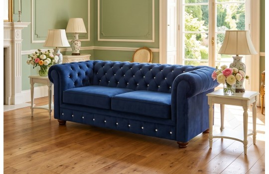 Granatowa sofa retro chesterfield – ciemnoniebieski welur z pikowaniem w jasnym salonie Granatowa sofa retro chesterfield – ciemnoniebieski welur z pikowaniem w jasnym salonie