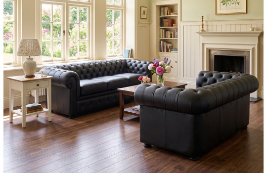 Zestaw sof chesterfield w czarnej skórze – dwie sofy w salonie z drewnianą podłogą Zestaw sof chesterfield w czarnej skórze – dwie sofy w salonie z drewnianą podłogą