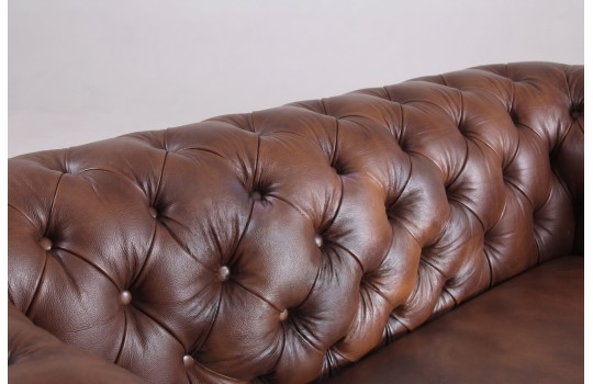 Głębokie pikowanie guzikami na sofie Chesterfield – zbliżenie na brązową skórę naturalną Głębokie pikowanie guzikami na sofie Chesterfield – zbliżenie na brązową skórę naturalną