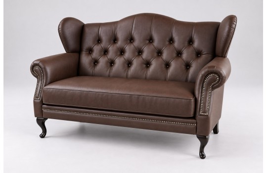 Ciemnobrązowa skórzana sofa uszak Aloha z ćwiekami wzdłuż podłokietników Ciemnobrązowa skórzana sofa uszak Aloha z ćwiekami wzdłuż podłokietników